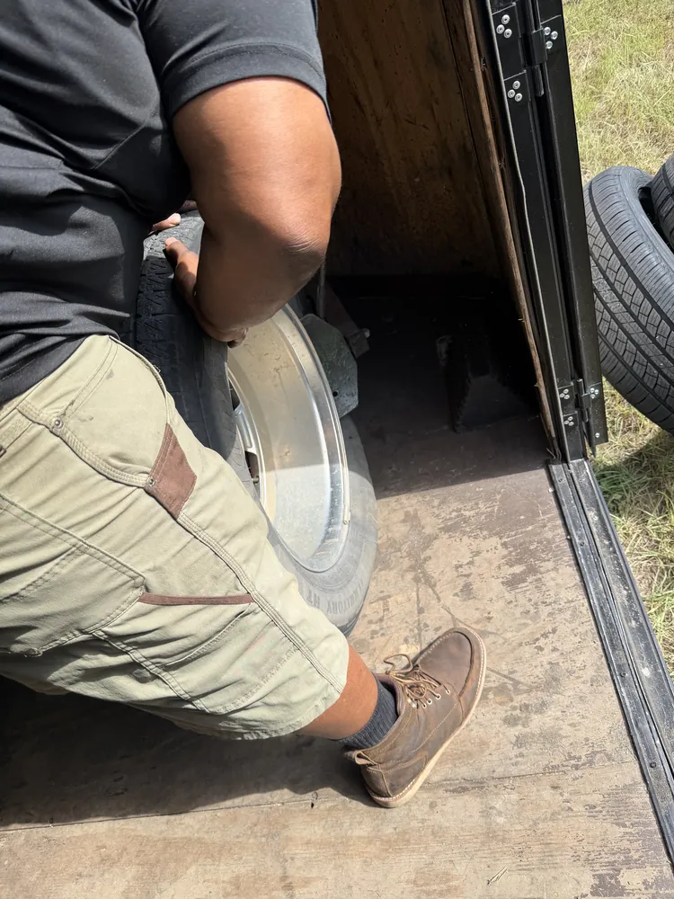 Taylor Mobile Tire Service technician bringing a wheel into the mobile tire shop trailer